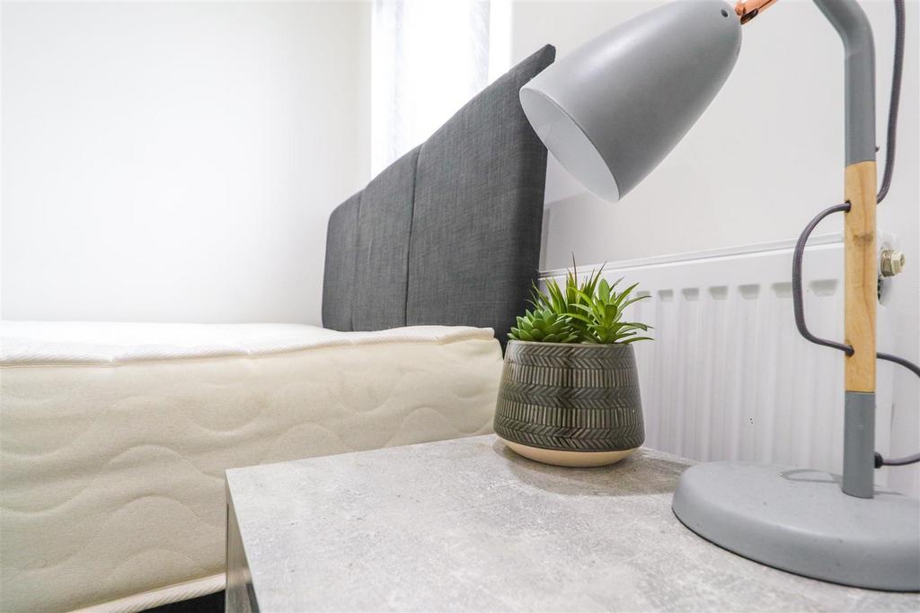 Bright, tidy bedroom corner with bedside table...