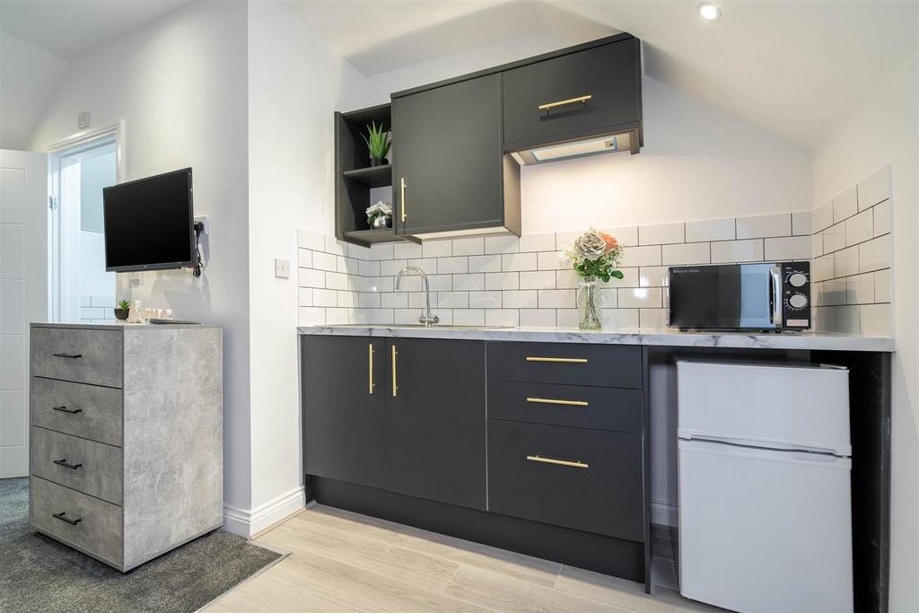 Modern compact kitchenette with dark cabinetry,...