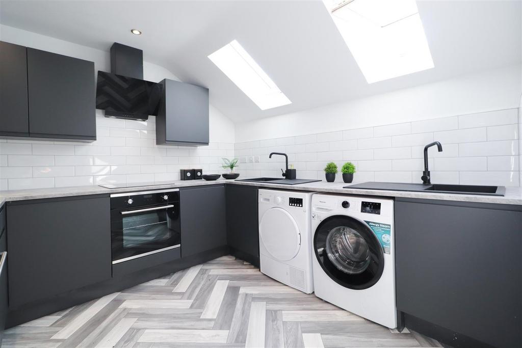 Modern fitted kitchen with skylights and laundr...