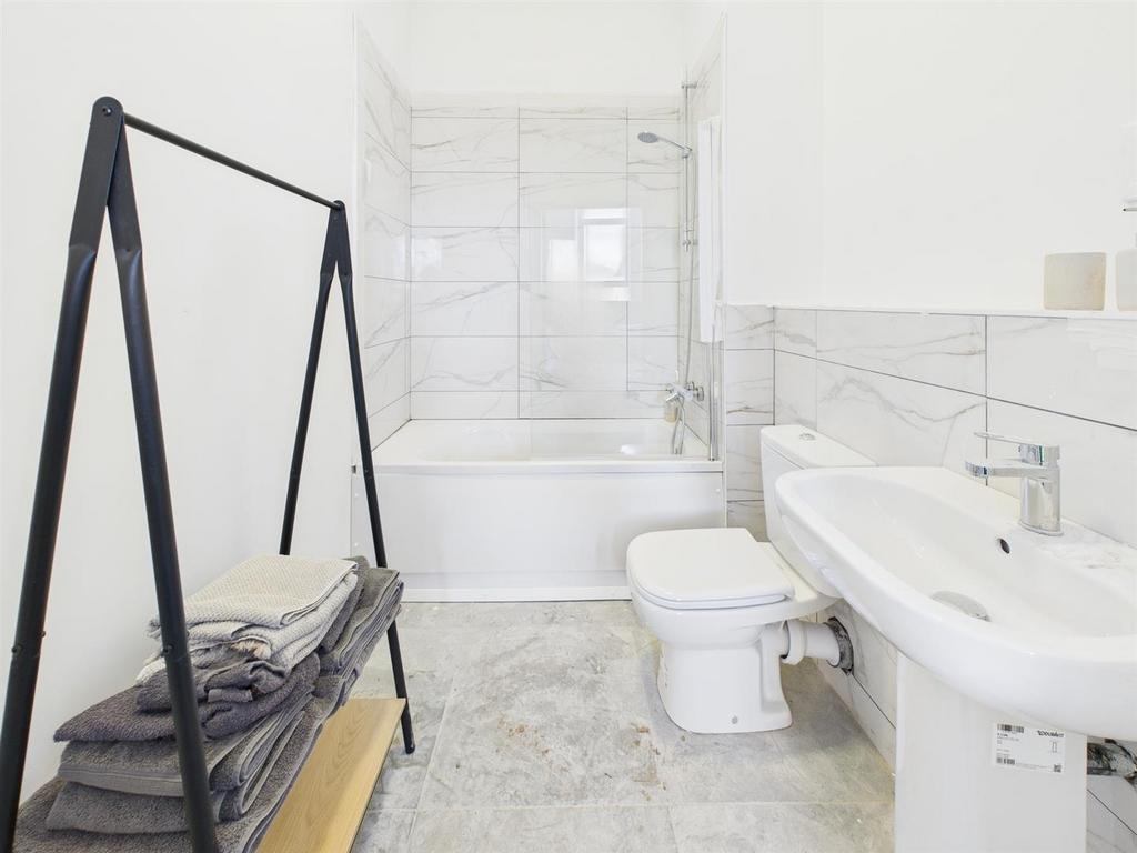 Bright modern bathroom with tub and marble tile...
