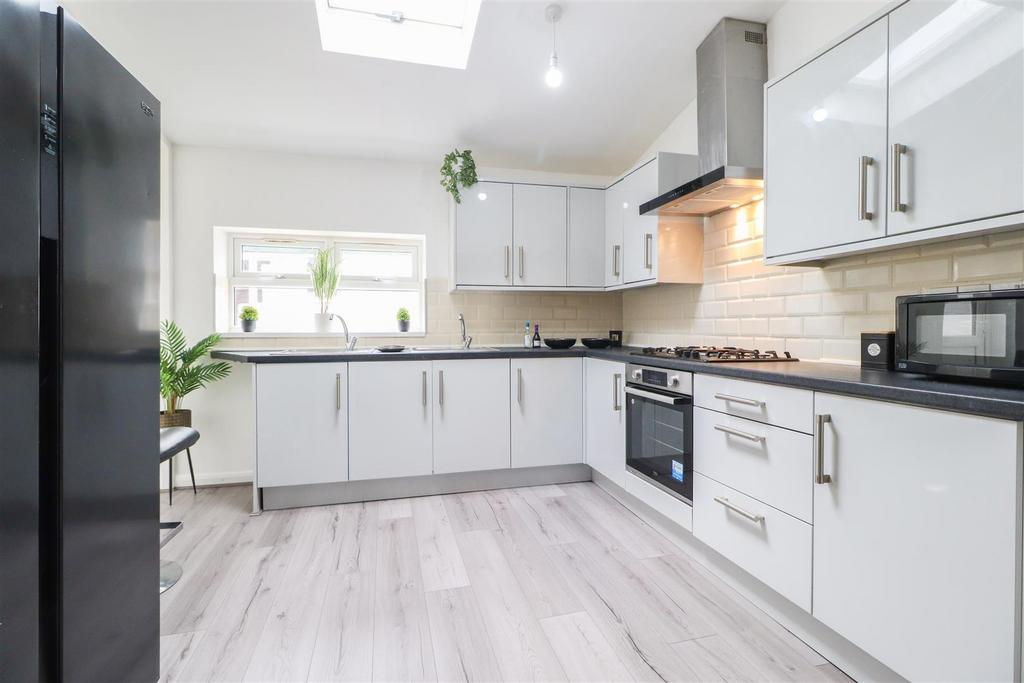 Bright, modern kitchen with white cabinetry, in...