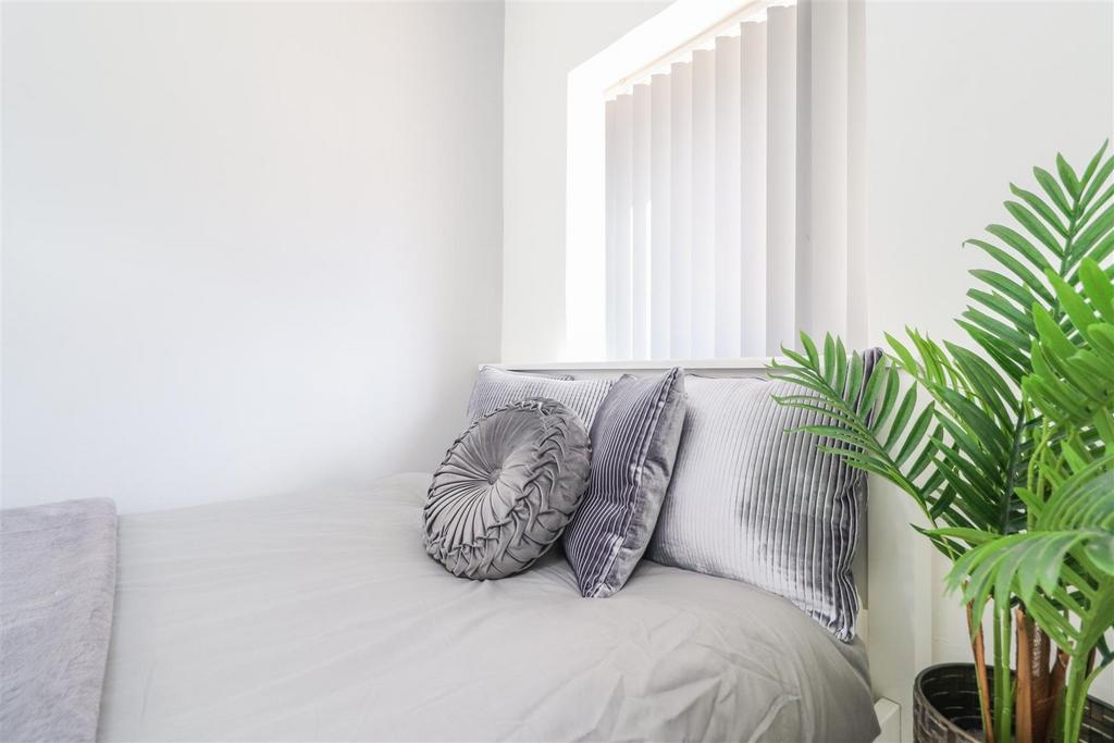 Bright, neatly made single bedroom with neutral...
