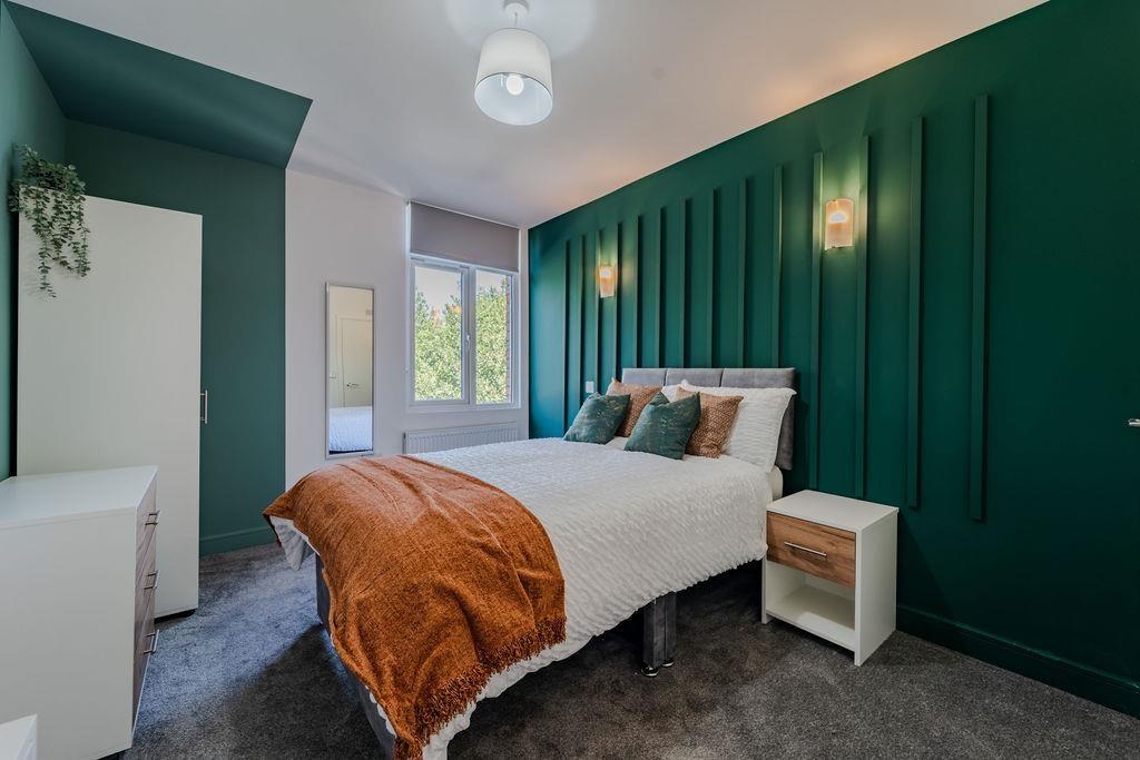 Stylish double bedroom with feature dark-green ...