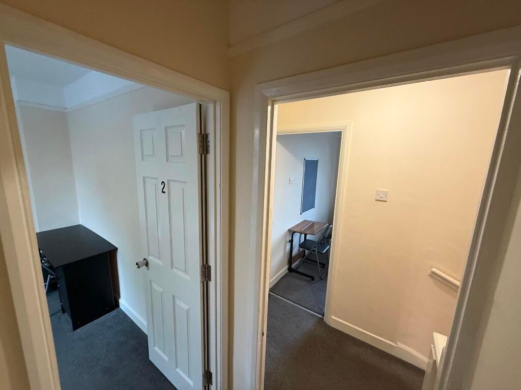 Bright, neutral hallway with two adjacent rooms...