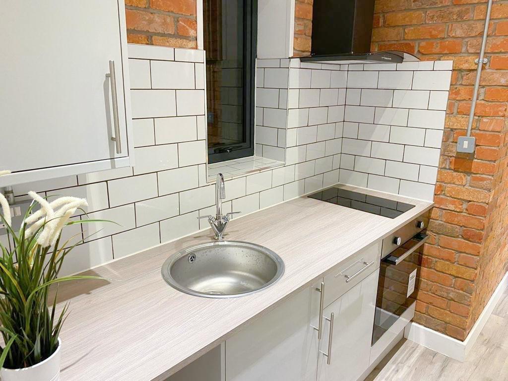 Modern kitchenette with subway tiles and oak wo...