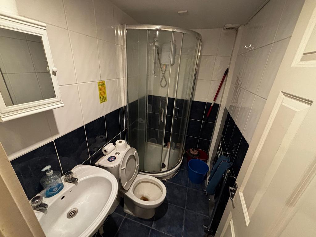 Compact tiled bathroom with a corner shower enc...