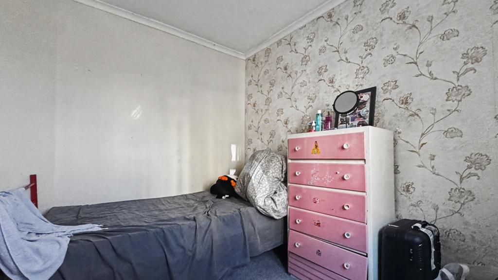 Cosy bedroom with patterned feature wall and ch...