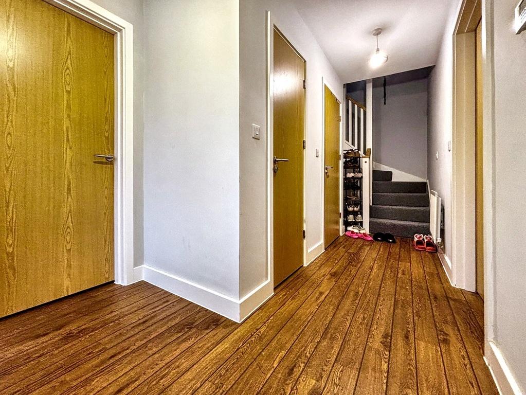 Bright, well-kept hallway with warm wooden floo...