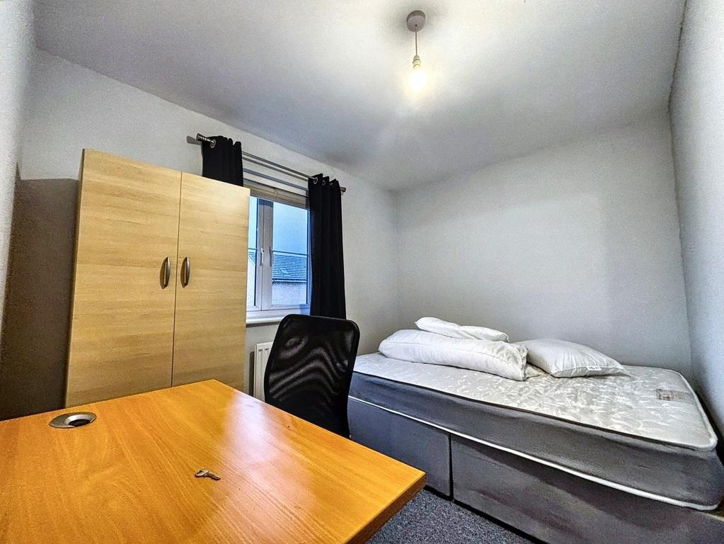 Bright, simply furnished bedroom with a desk, c...