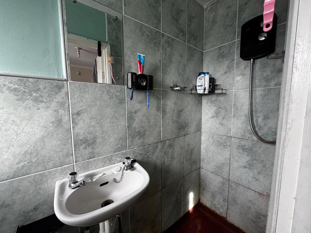 Modern tiled bathroom with wall-mounted shower,...
