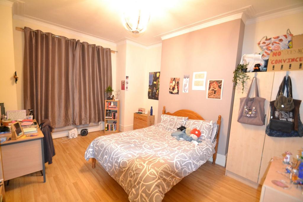 A cozy, well-lit bedroom featuring a neatly mad...