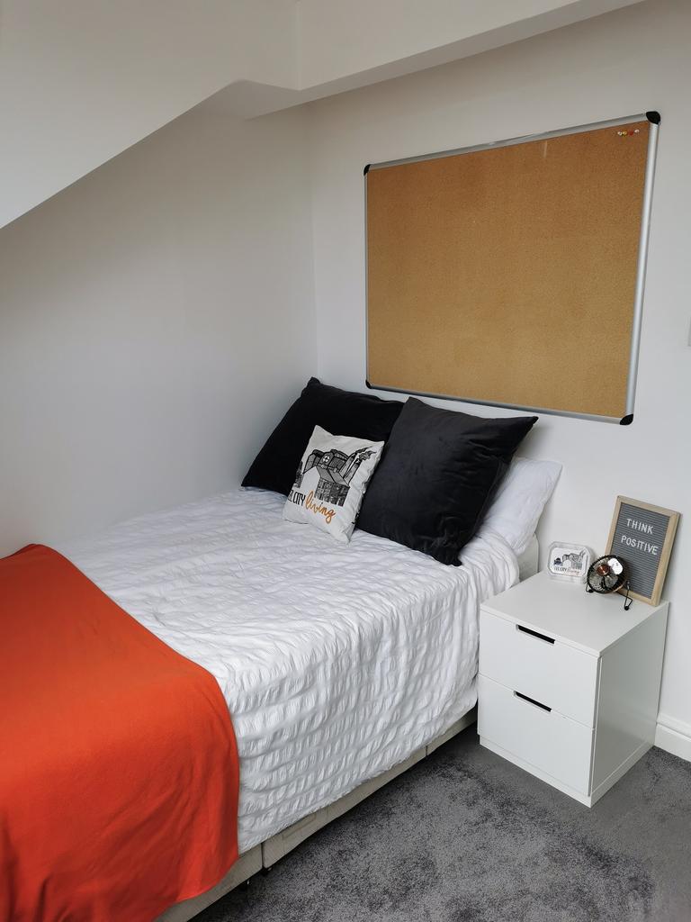Bright, neatly made double bedroom with white b...