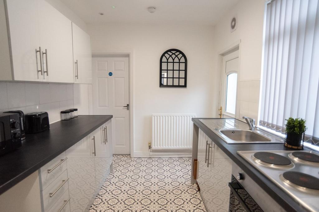 Bright, modern galley kitchen with patterned fl...