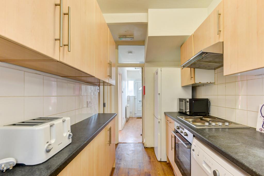 Long galley kitchen with light wood cabinets, d...