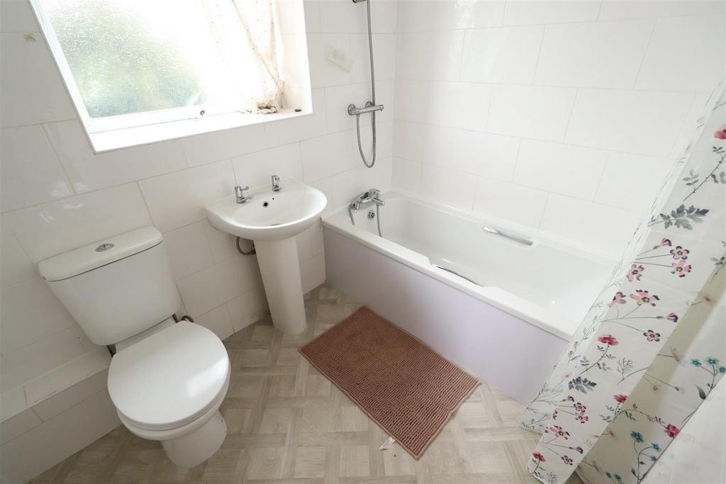 Clean white bathroom with bath and natural ligh...