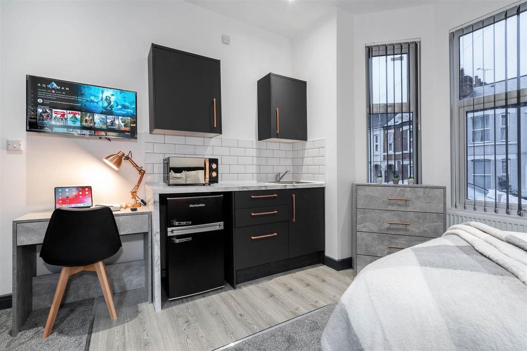 Bright, modern bedroom with integrated kitchene...