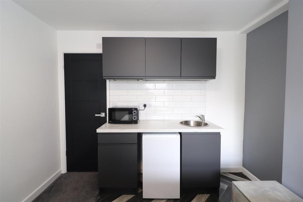 Compact modern kitchen with dark cabinetry...