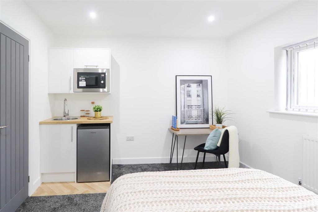 Bright, modern bedroom with kitchenette and des...