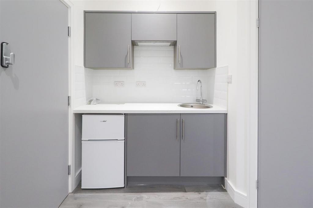Compact modern kitchenette with grey fitted cab...