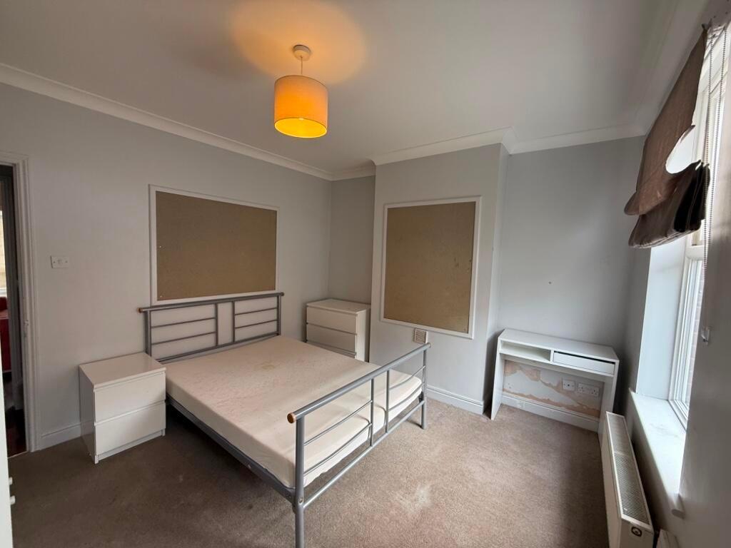 Bright double bedroom with a metal bed frame, n...