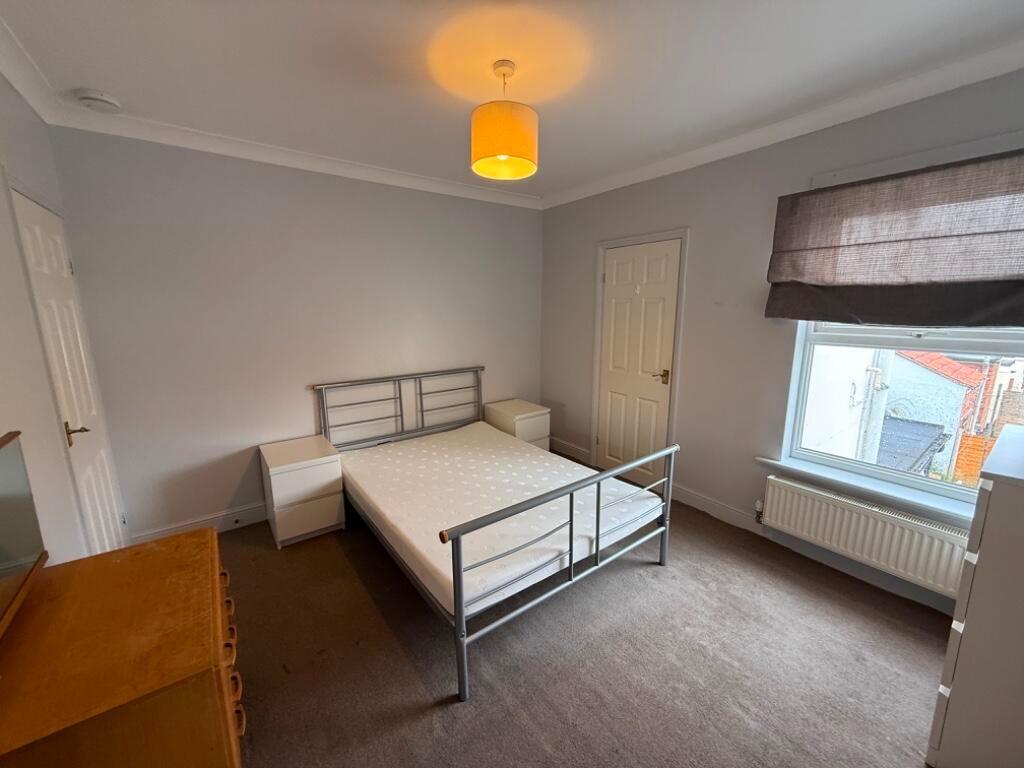 Bright, neutral double bedroom with a metal dou...