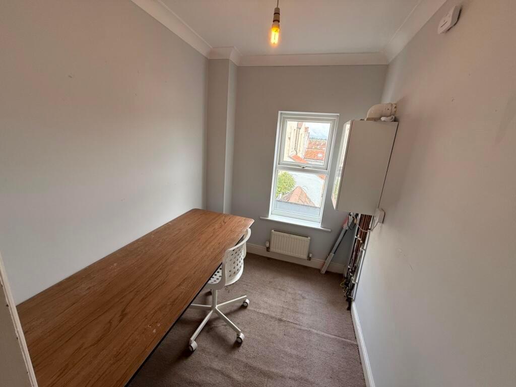 Bright narrow study room with a long wooden des...