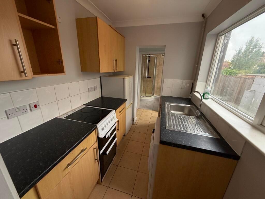 Neat galley kitchen with modern black worktops,...