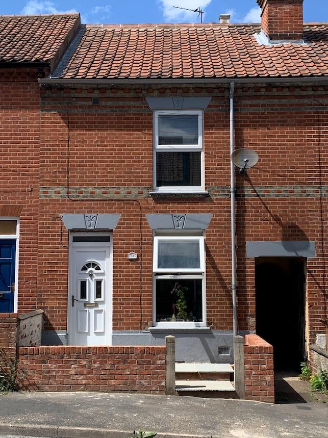 Red-brick terraced house with tiled roof, white...