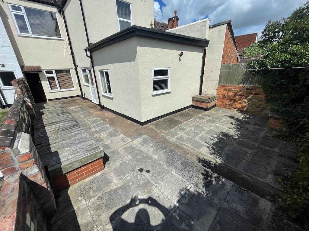 Private paved courtyard with low brick walls, a...