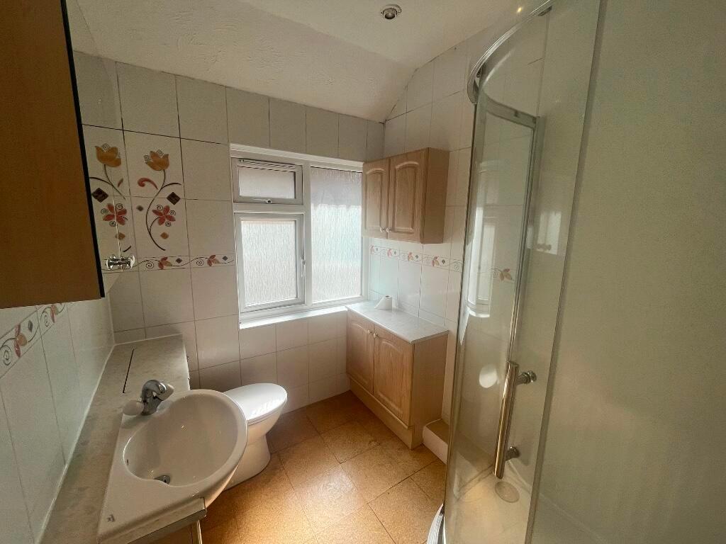 Bright tiled bathroom with a corner shower encl...