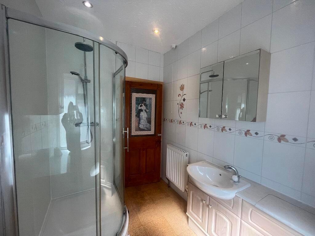 Bright, tiled bathroom featuring a curved glass...