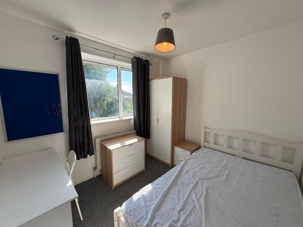 Bright, neatly furnished bedroom with a double ...