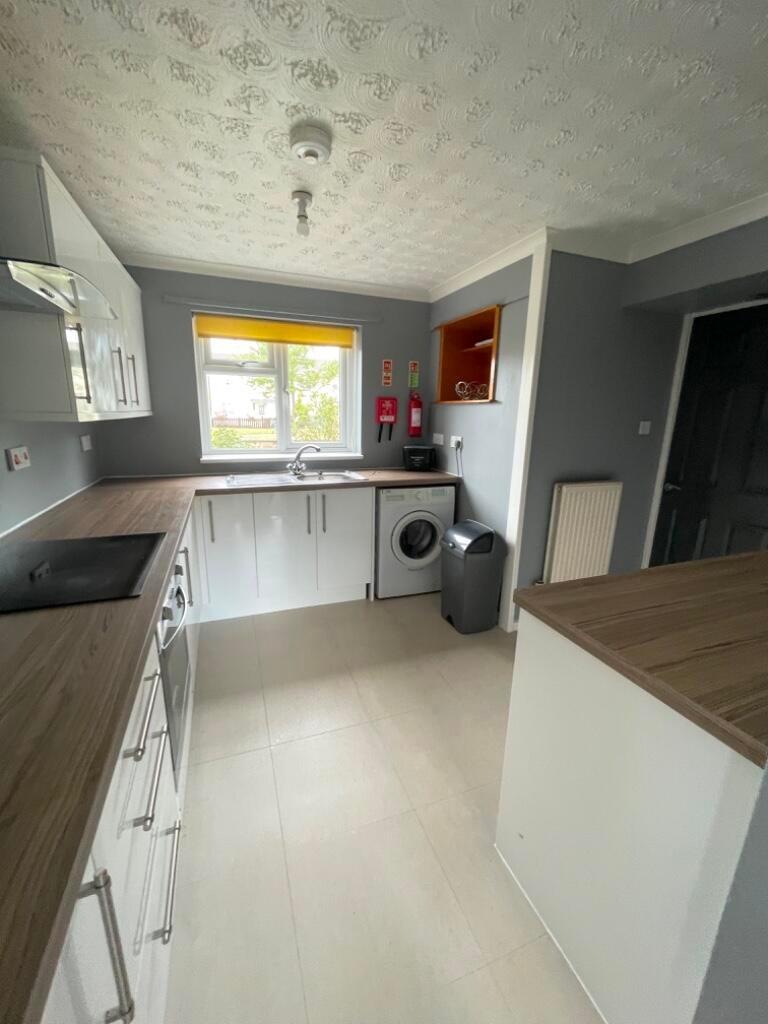Bright, modern kitchen with fitted white cabine...