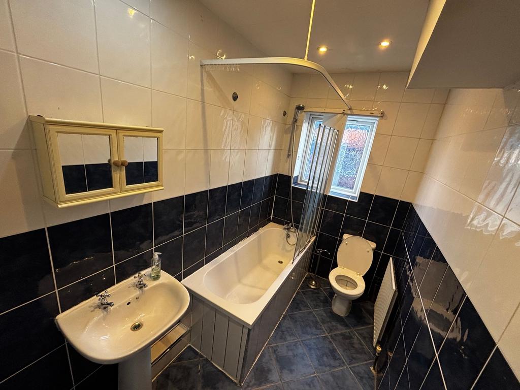 Bright tiled bathroom with a bathtub and shower...