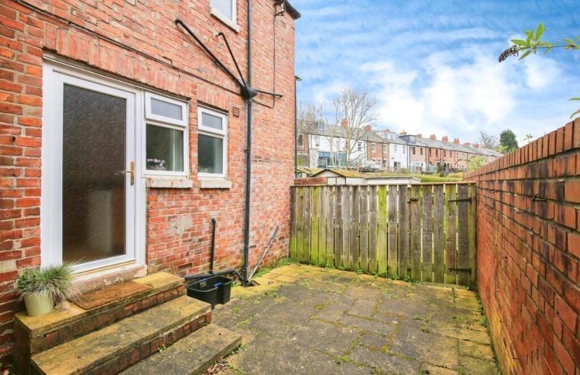 Private paved rear yard with secure brick and t...