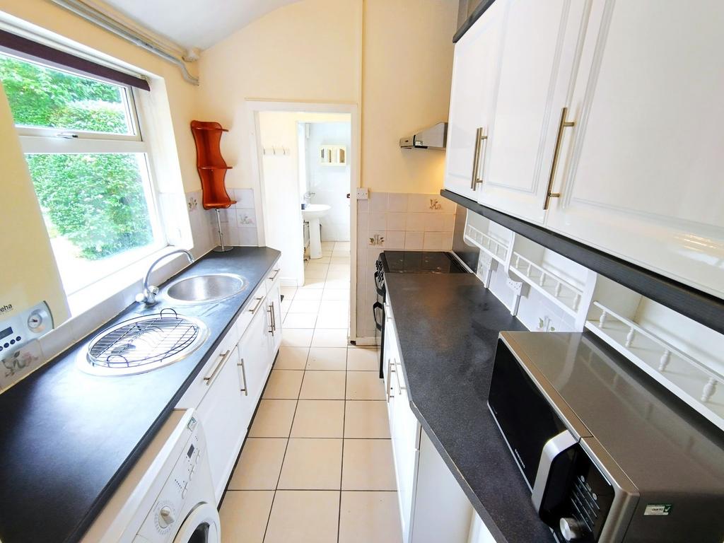 Bright galley kitchen with dark worktops, white...
