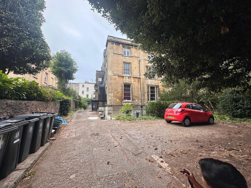 Stone-built period building set behind mature t...