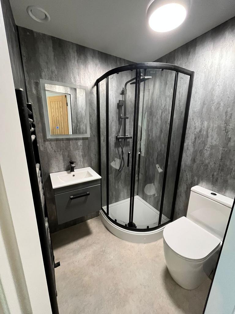 Modern bathroom with a curved glass shower encl...