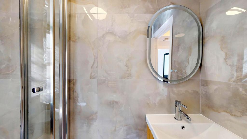 Contemporary tiled bathroom featuring a glass-e...