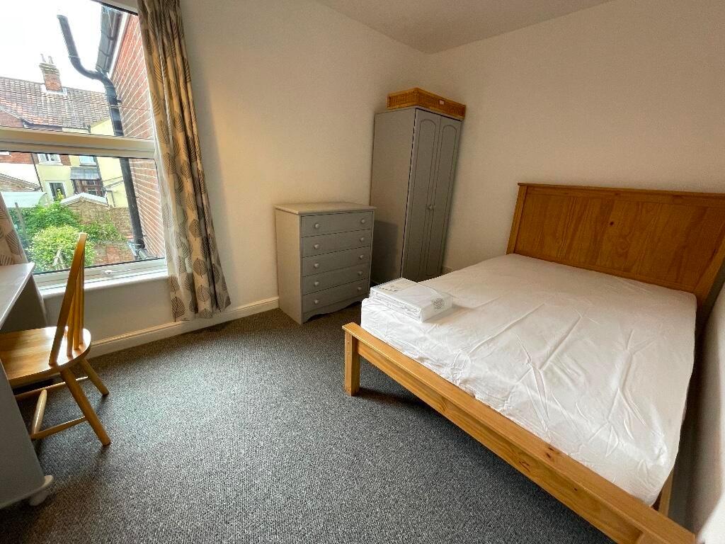 Bright, neatly presented bedroom with a wooden ...