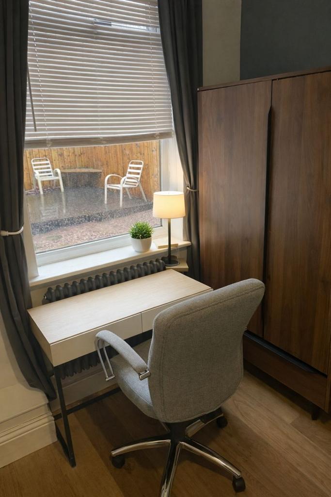 Compact bedroom with desk by a bright window...