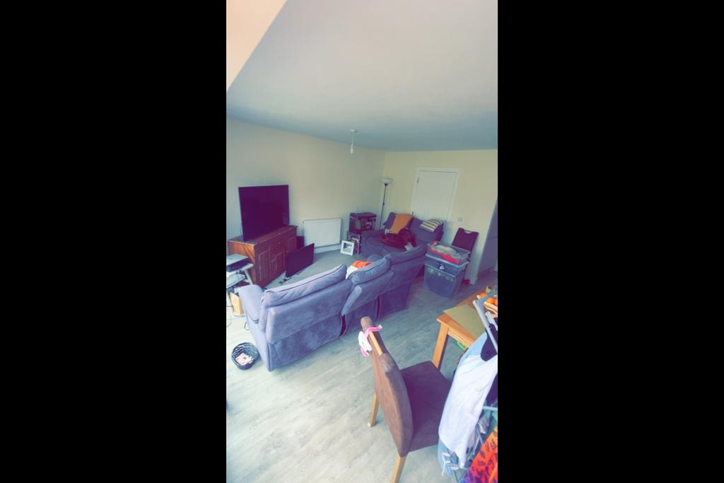 Bright, casual living room with a large TV on a...