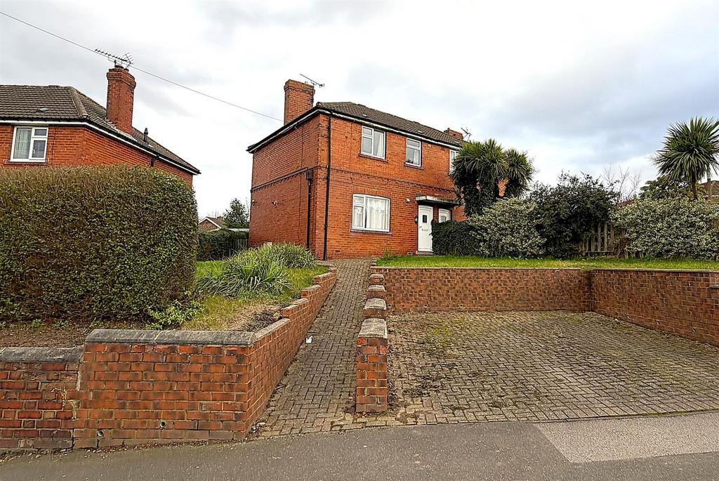 Detached red-brick house with driveway and hedg...