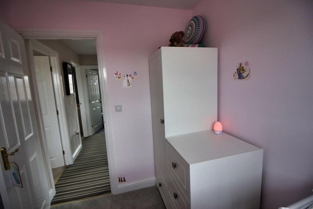 Cozy bedroom with soft pink walls and storage...
