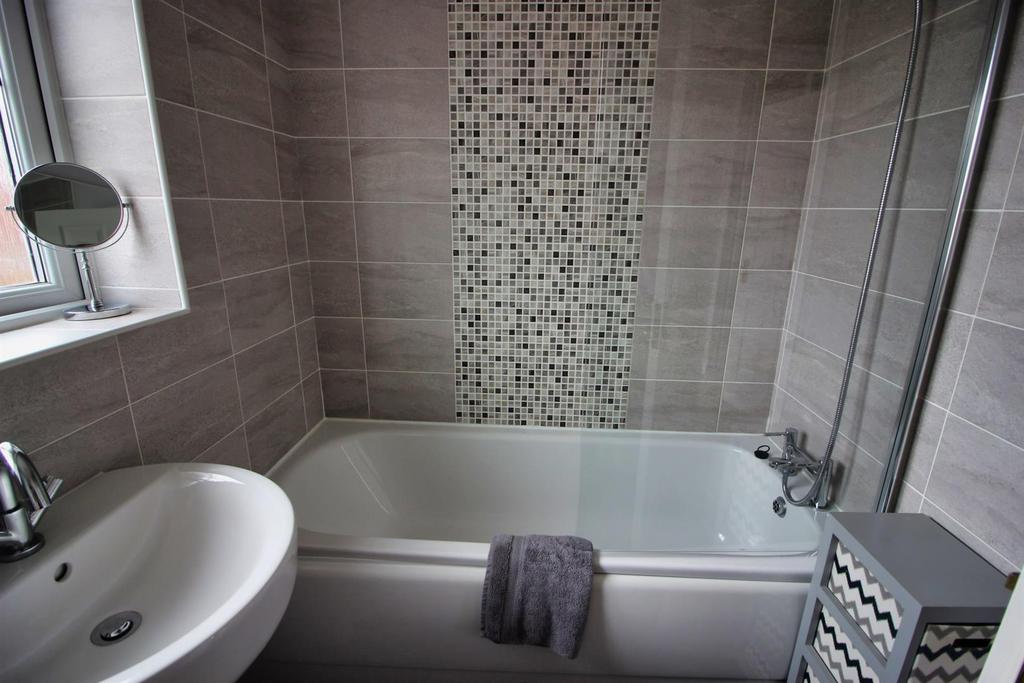 Modern tiled bathroom with bath and window...