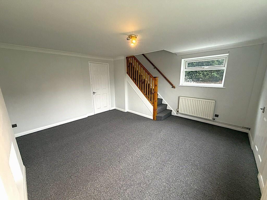 Bright, neutral living room with staircase feat...