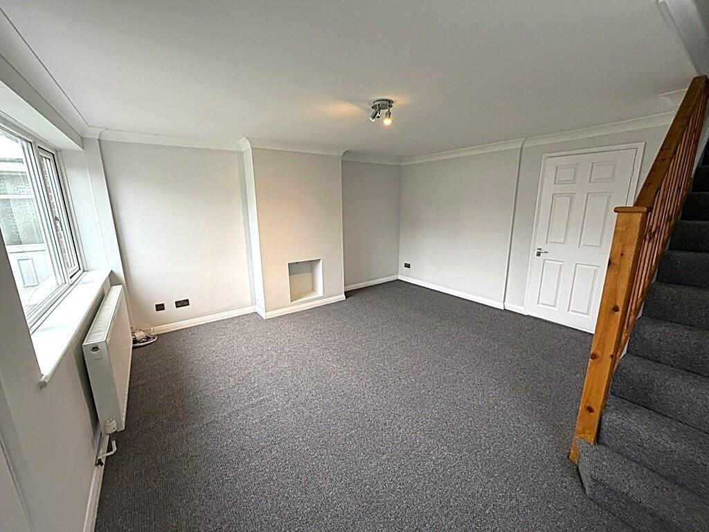 Bright, neutral living room with stair access...