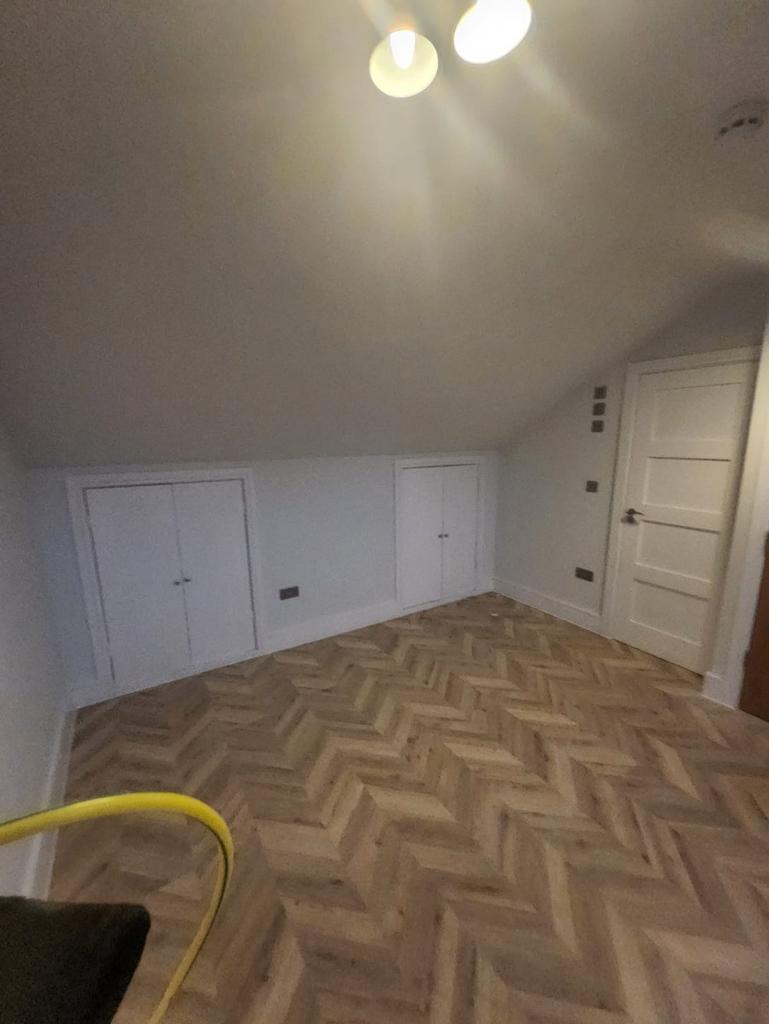 Cozy attic room with patterned wood flooring...