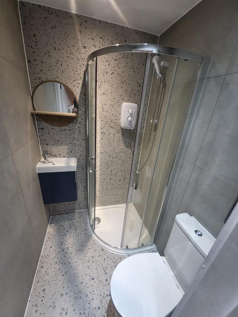 Modern compact bathroom with curved shower...