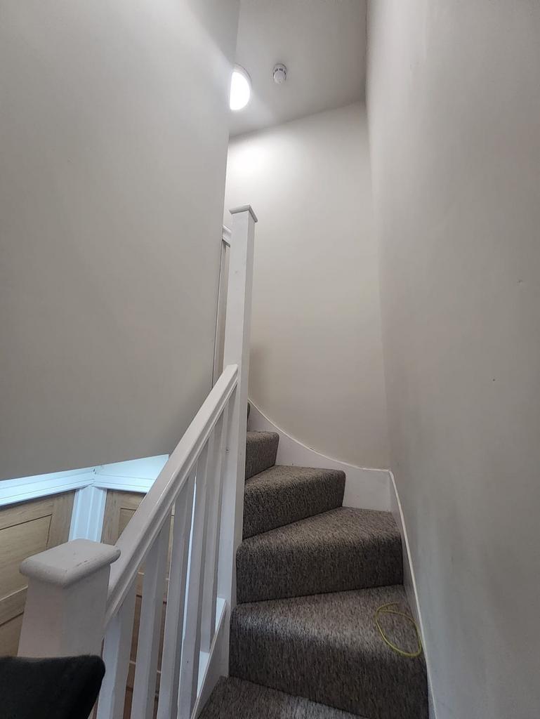 Carpeted winding staircase with white balustrad...